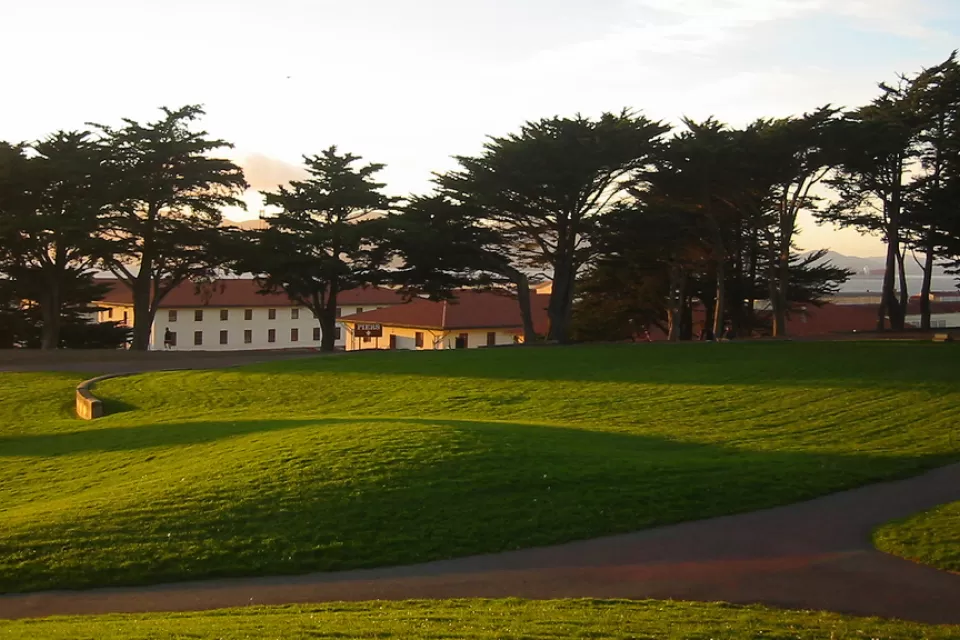 Green lawn with fort mason buildings in background beyond trees